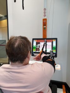 Person at a computer with arm in ceiling-suspended sling